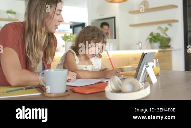 Diverse family mother leaning pointing child writing homework at ...