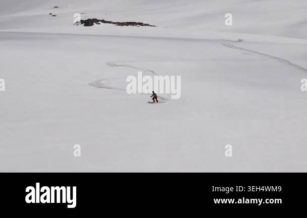 Lone skier carving fresh tracks across pristine alpine snowfield cold ...