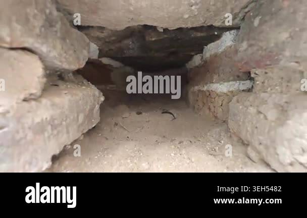 Camera pulls back through a small hole in an old wall revealing ancient ...
