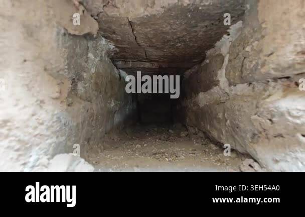 Camera pulls back through a small hole in an old wall revealing ancient ...