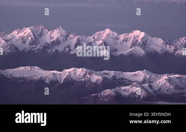 Aerial view of snowy Alps peaks in slanting sunlight, winter mountain ...