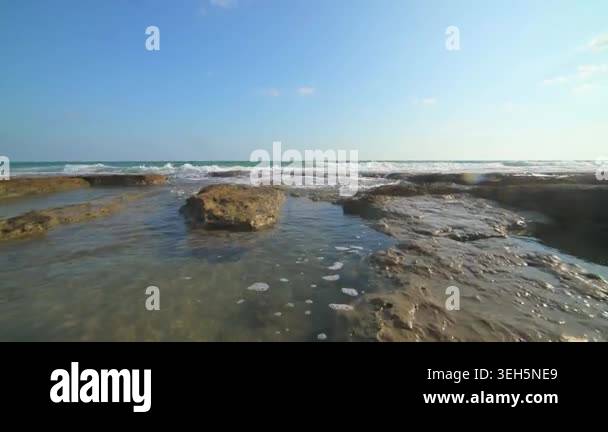 Coastal reef and rugged rocky shoreline with clear seawater and ...