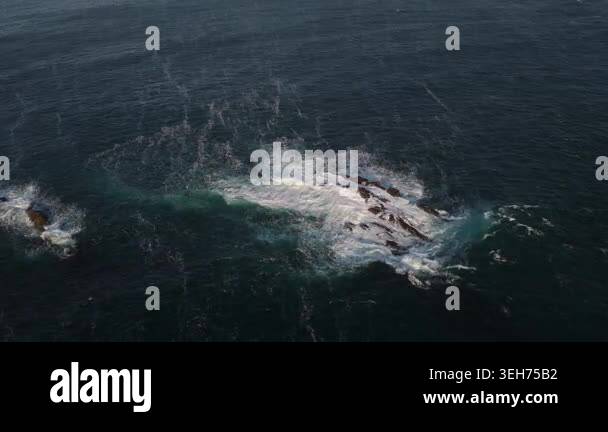Waves crash against rugged rocks in a powerful ocean display. The deep ...