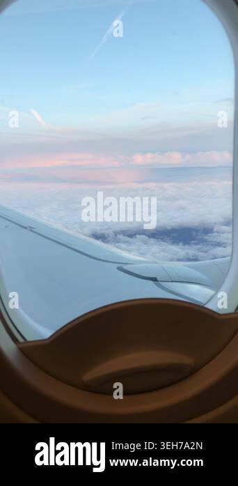 Airplane window frames clouds and wing during a calm evening flight ...
