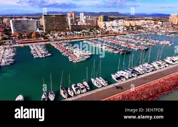 Harbor filled with white sailboats and yachts next to a city with high ...
