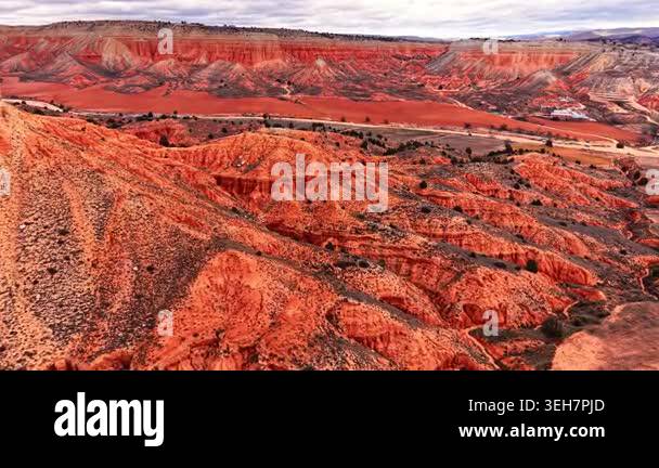 High angle view of a vast arid landscape featuring red soil, eroded ...