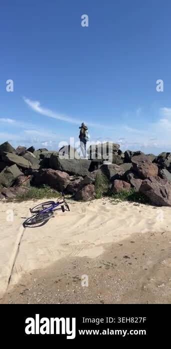 Young Woman Standing on Rocks Looking at Sea Horizon with Bicycle ...