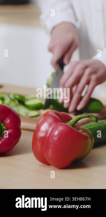 closeup woman slicing cucumber with headphones, red bell peppers on ...