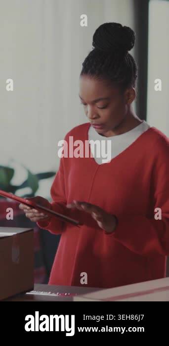 woman tapping tablet beside packed boxes, focused entrepreneur ...