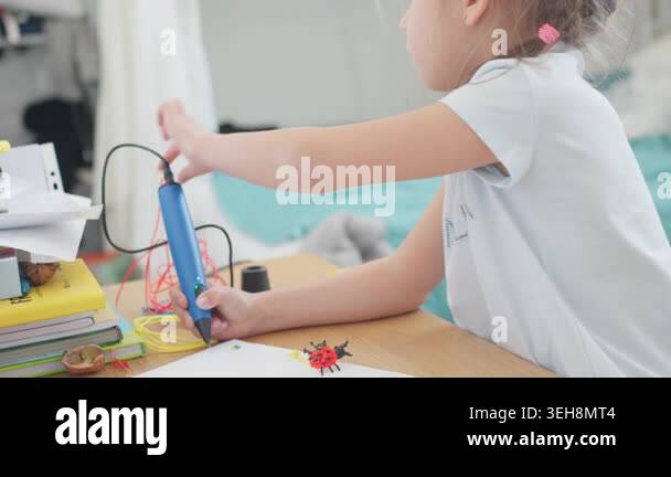 Little girl is using a 3D pen on a table filled with craft supplies ...