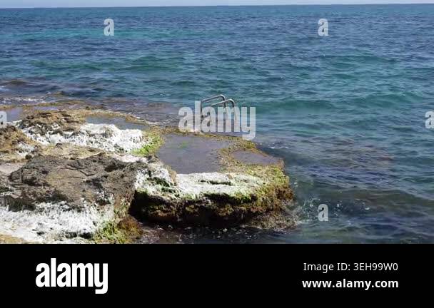 Rocky Mediterranean shoreline in Spain with sea access ladder ...