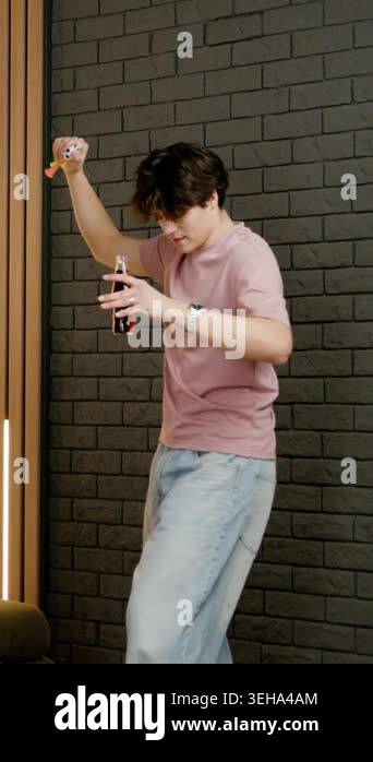 Young man with dark hair dances joyfully while holding soft drink ...
