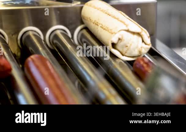 Close-up of a hot dog wrapped in lavash being cooked on a grill at a ...
