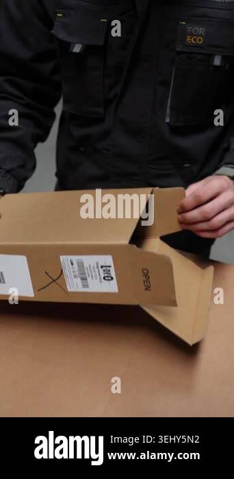 Worker opens cardboard box with metal component inside. Hands carefully ...