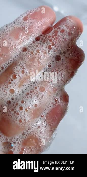 Gently rubbing soap foam bubbles on wet palm of hand. Close up view ...