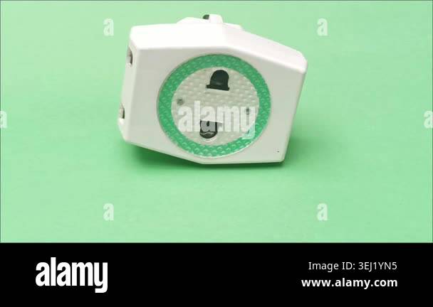 Three way universal electric plug adapter converter on a green ...