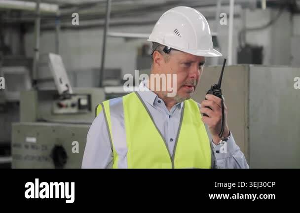 Factory engineer in safety helmet and reflective vest communicating by ...