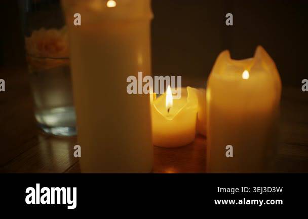 Artistic shot of small ivory candles glowing on a wooden surface ...