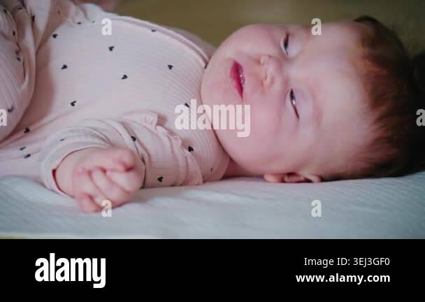 Close up of an infant lying on a cushioned surface, slightly smiling or ...