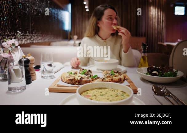 Woman eating soup at a restaurant table with a bowl of creamy soup in ...