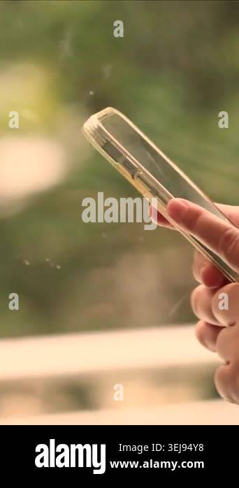 Smartphone in hand inside moving vehicle with blurred greenery outside ...
