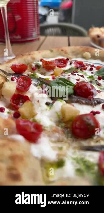 Closeup burrata and pepperoni pizzas on outdoor table with hand slicing ...