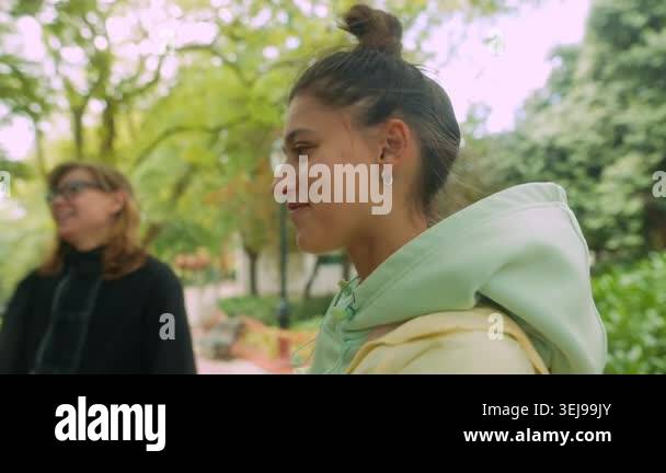 Young woman and mentor in park, candid side profile exchange, casual ...