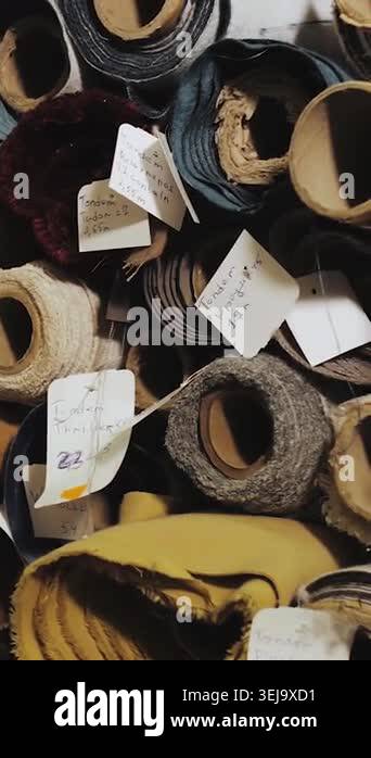 Vertical video. Rolled fabric and upholstery materials stacked in ...