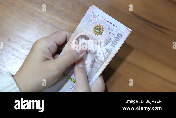 Hands counting money banknotes Thai baht on table, representing finance ...