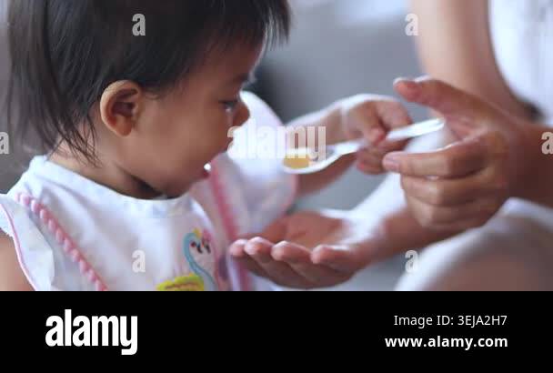 Child feeding snack independently, A little child feeds itself, mother ...