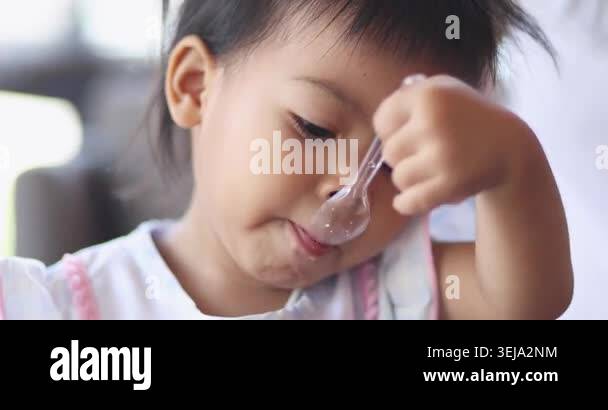 Child feeding snack independently, A little child feeds itself, mother ...