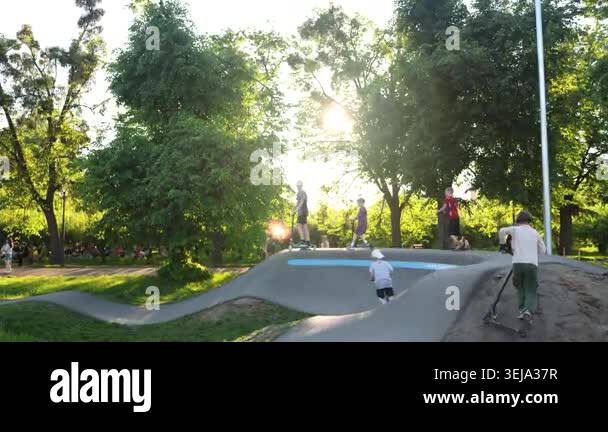 Teens kids playing in scooter park outdoor in summer day with skates ...