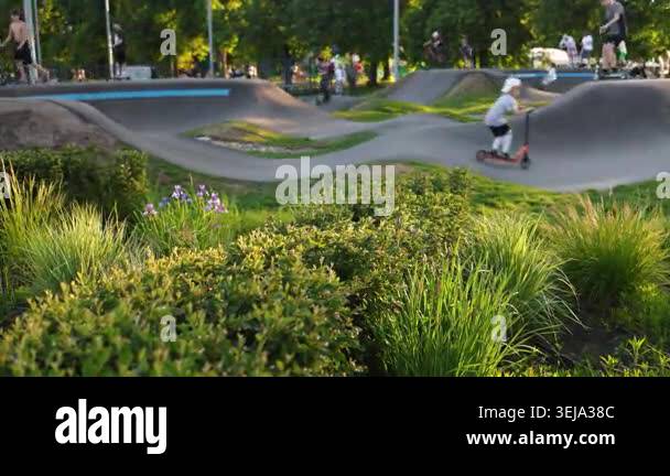 Teens kids playing in scooter park outdoor in summer day with skates ...