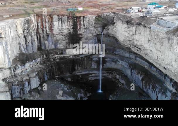 Drone view of a vast open-pit quarry with steep white rock walls, a ...