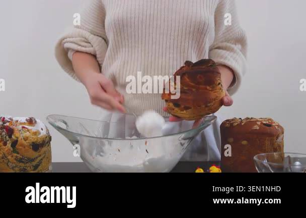 woman gently spreads thick white icing over the top of a freshly baked ...