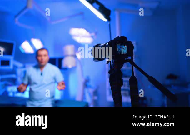Camera on tripod filming standing doctor in surgical suite. Foreground ...