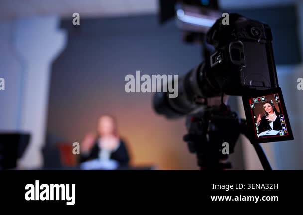 Telephoto camera filming smiling woman in studio interview. Long-lens ...