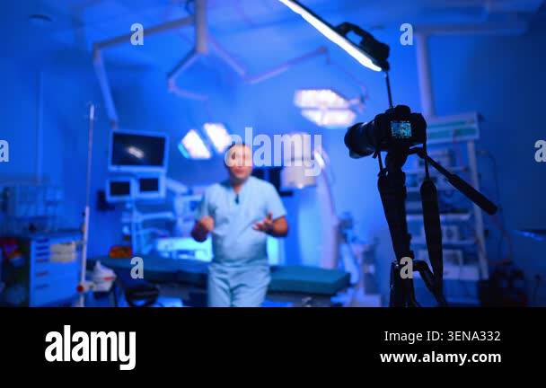 Camera filming doctor speaking in blue-lit operating theatre. Rig on ...