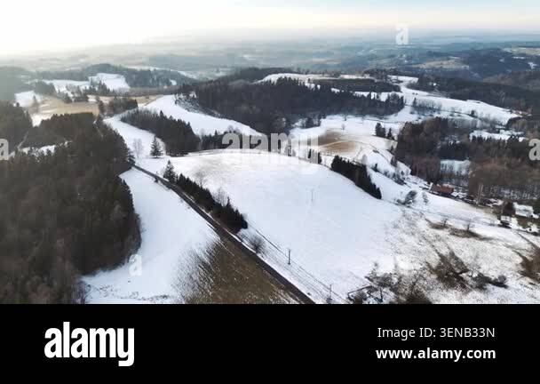 An aerial drone shot overlooking rolling hills covered in snow with ...