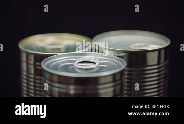 Three open metal tin cans arranged on a dark studio background, with ...