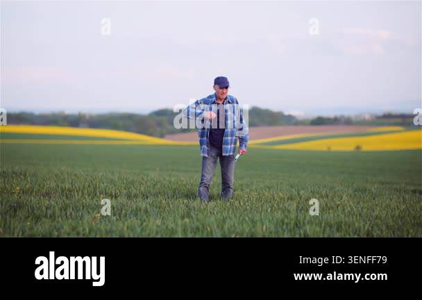 Adult man stands in a green rural field carrying a shoulder bag, with ...