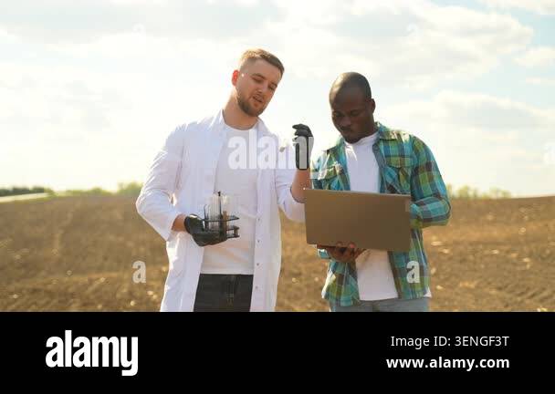 Agronomist in a lab coat and a farmer analyzing soil quality together ...
