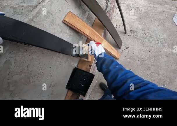 The master paints a wooden part with black paint. Close-up of hands in ...