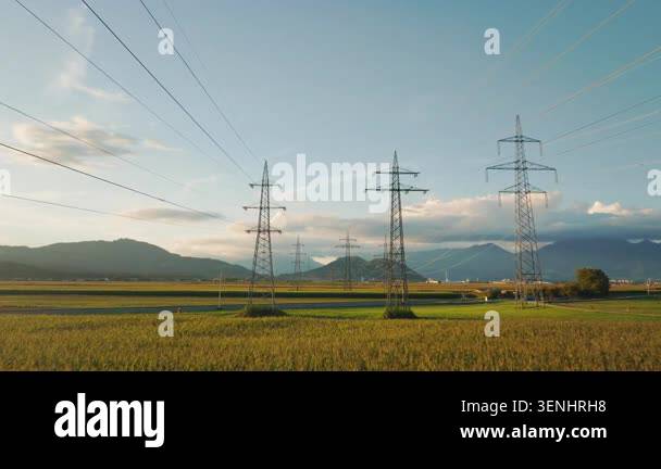 Power lines and towers are visible in a rural area as the sun sets in ...