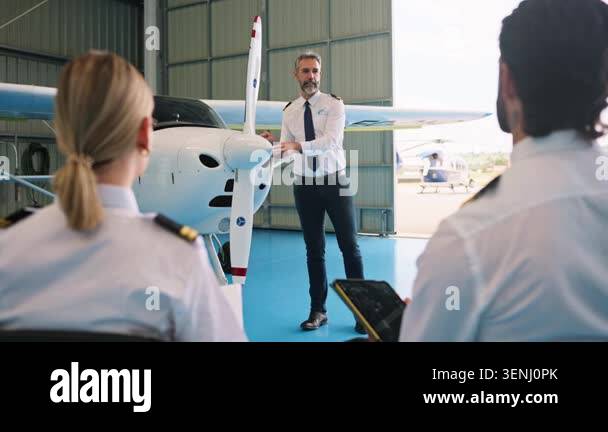 Aviation professor teaching a class of pilot students inside a hangar ...