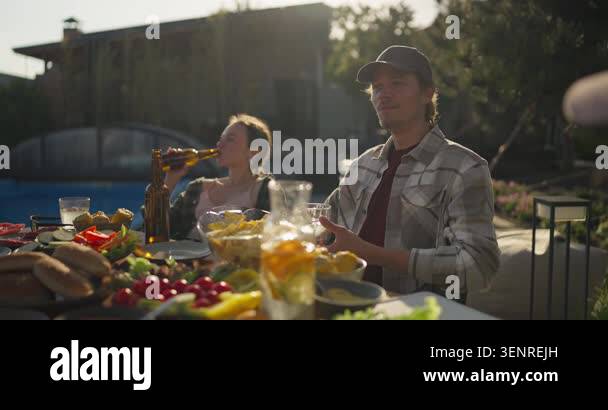 Outdoor evening gathering in a home backyard beside the pool, with a ...