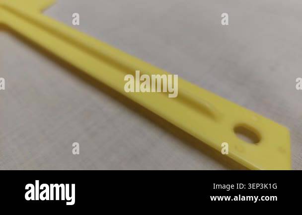 Camera pan along a bright yellow plastic spatula or scraper tool lying ...