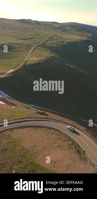 Vertical Screen: Aerial drone footage of white SUV driving winding ...