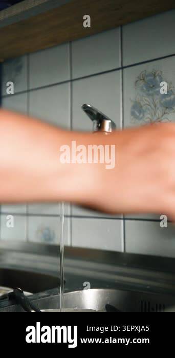 Vertical video of man hands turning on tap, washing glass, putting it ...