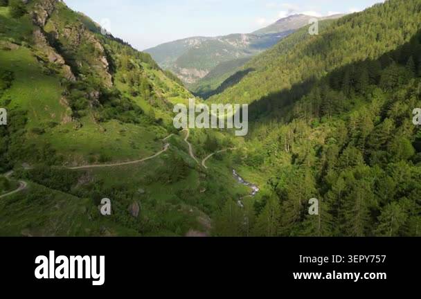 Aerial drone footage over a winding mountain path and a lush green ...